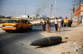 Palestinians view an unexploded Israeli shell in Gaza