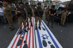Photo of an October 2023 Iraqi demonstration with footprints covering the Israeli and American flags.