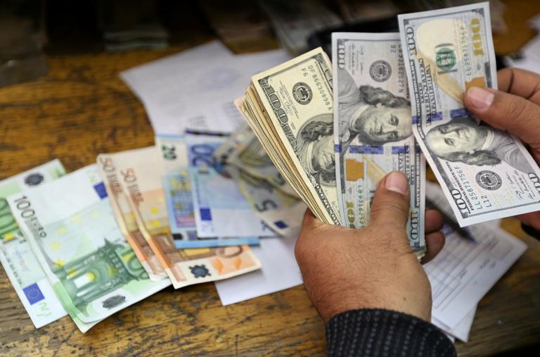 A money changer counts dollar and euro notes