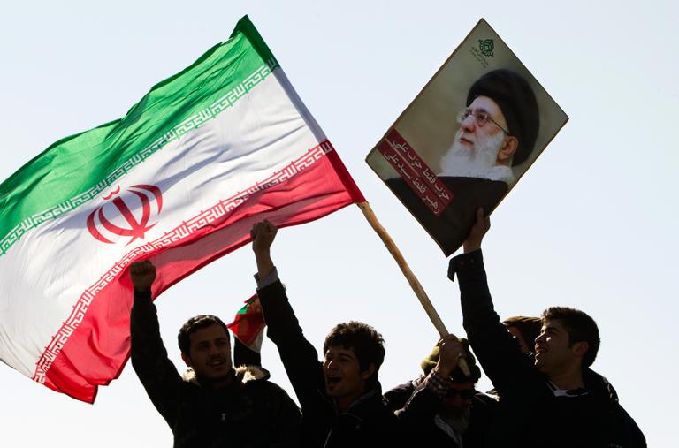 Protesters wave the Iranian flag and a photo of Iran's supreme leader Ali Khamenei