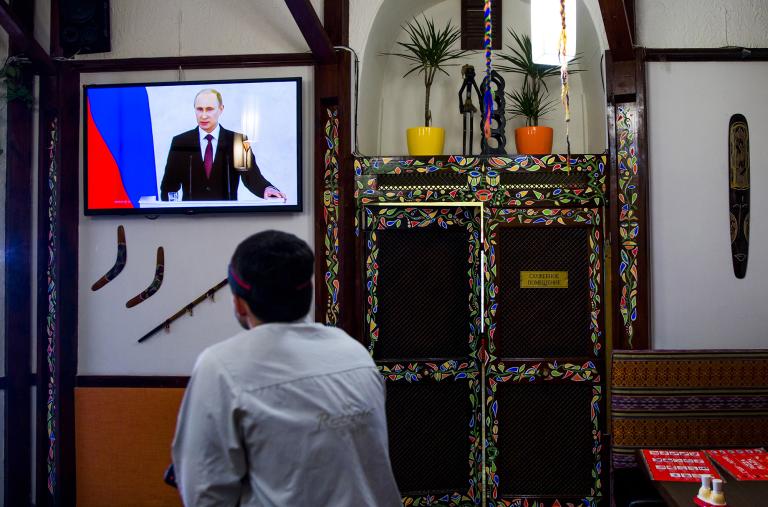 A man watches Russian president Vladimir Putin speak on television in the Crimean city of Simferopol - source: Reuters