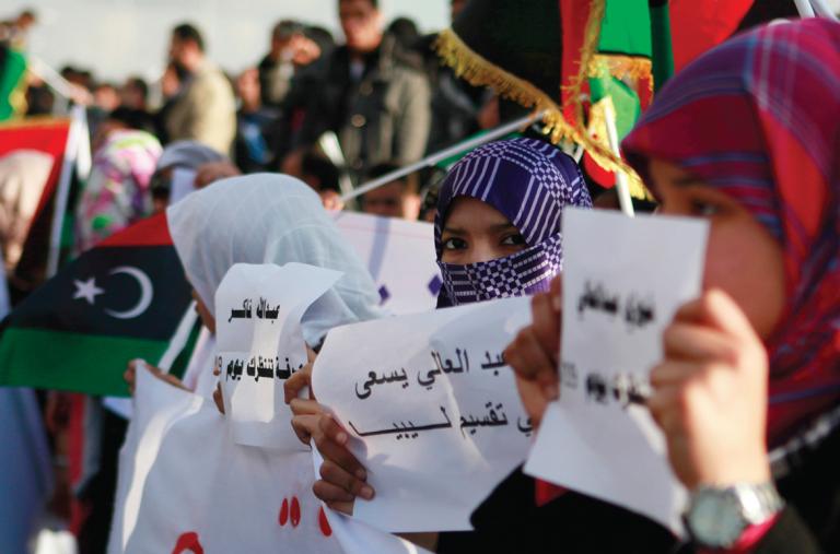 Protesters hold signs and flags in Libya - source: Reuters
