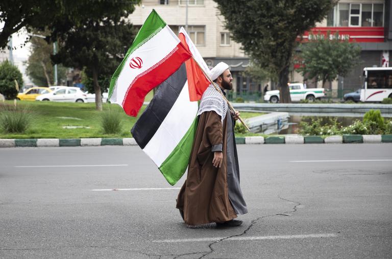 A man carries Iranian and Palestinian flags at a pro-Hamas rally in Tehran in October 2023 - source: Reuters