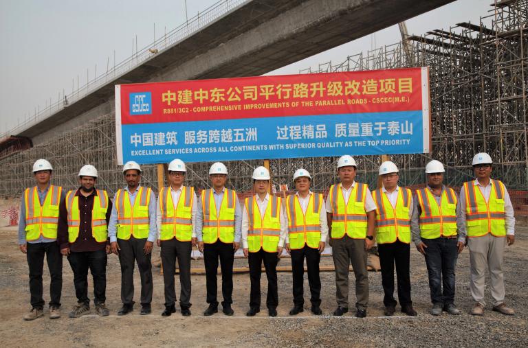 Chinese engineers pose in front of a sign announcing a Belt and Road Project construction project - source: China State Engineering Corp (Middle East) LLC
