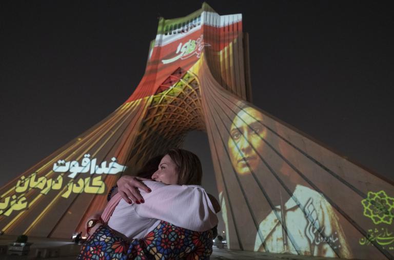 Two Iranian women hug each other while a country's flag and a portrait of an Iran-Israel war victim are projected on the Azadi (Freedom) Monument in western Tehran, Iran, on June 25, 2025 - source: Reuters