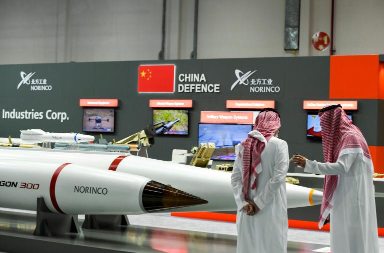 Men stand next to exhibits at the International Defence Exhibition in Abu Dhabi - source: Reuters