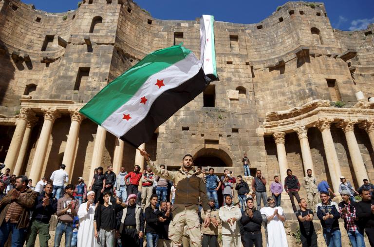 Protesters wave a Syrian opposition flag during a demonstration at a Roman ruin in Deraa Province in 2016 - source: Reuters