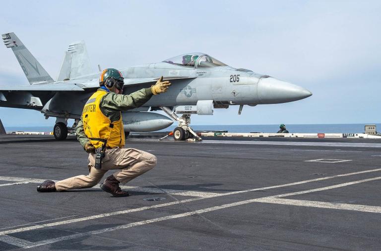 A sailor directs the launch of an F-18 from the flight deck of the carrier USS Harry S Truman - source: Department of Defense