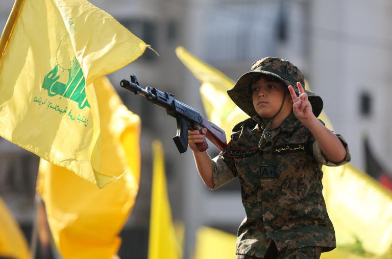 A child marches in a Hezbollah parade, holding a toy gun - source: Reuters