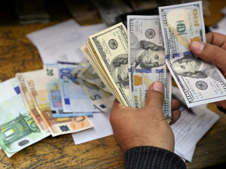 A money changer counts dollar and euro notes