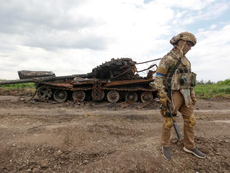 Ukrainian soldier beside destroyed Russian tank in Novodarivka, Ukraine