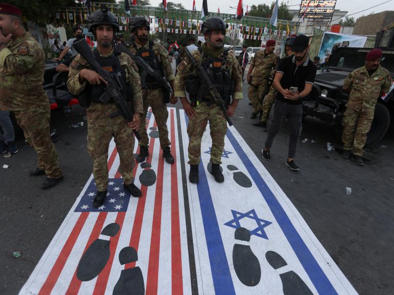 Photo of an October 2023 Iraqi demonstration with footprints covering the Israeli and American flags.