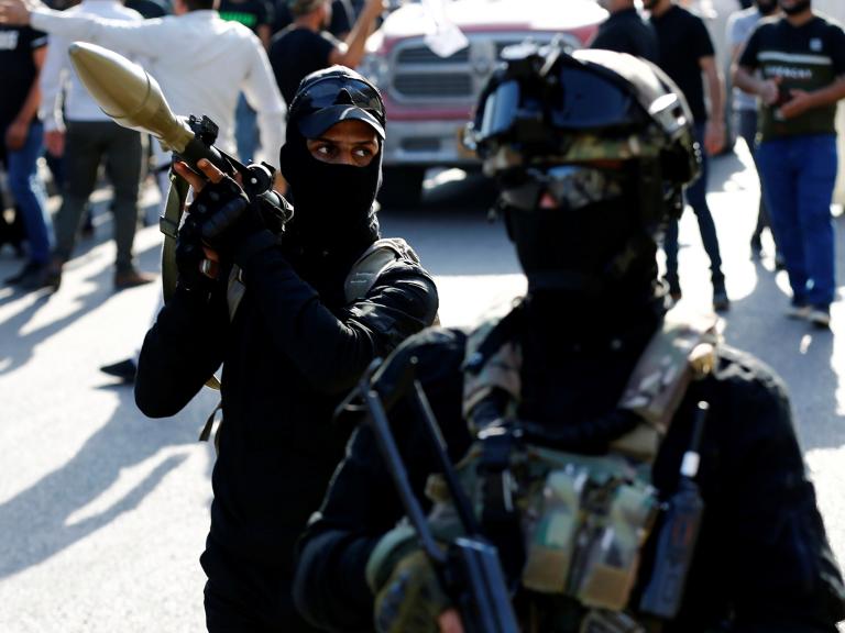 Armed members of the Iraqi Shiite militia Asaib Ahl al-Haq demonstrate at a funeral in Iraq - source: Reuters