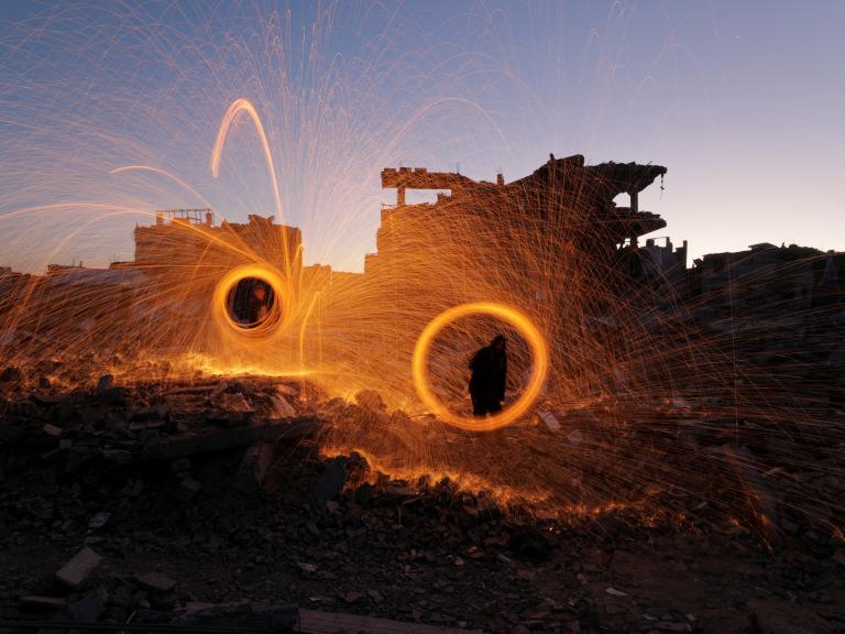 Photo showing Gaza residents spinning sparklers at the start of Ramadan, March 2025.