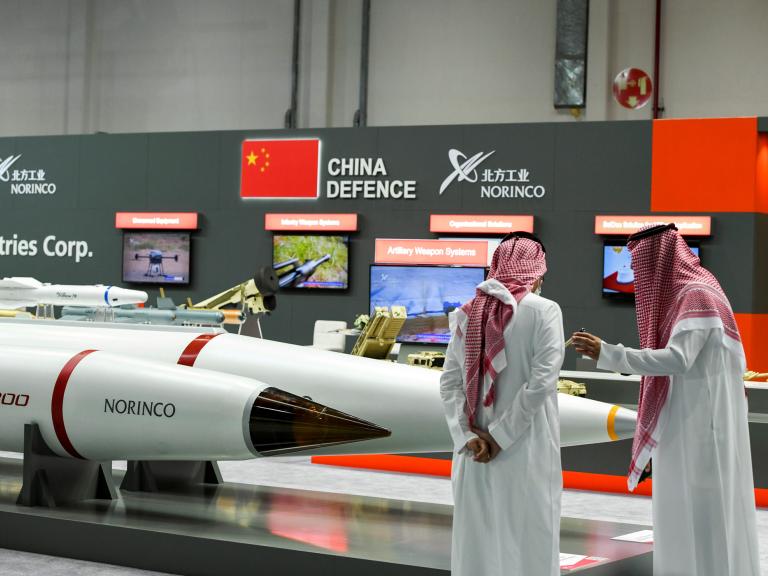 Men stand next to exhibits at the International Defence Exhibition in Abu Dhabi - source: Reuters