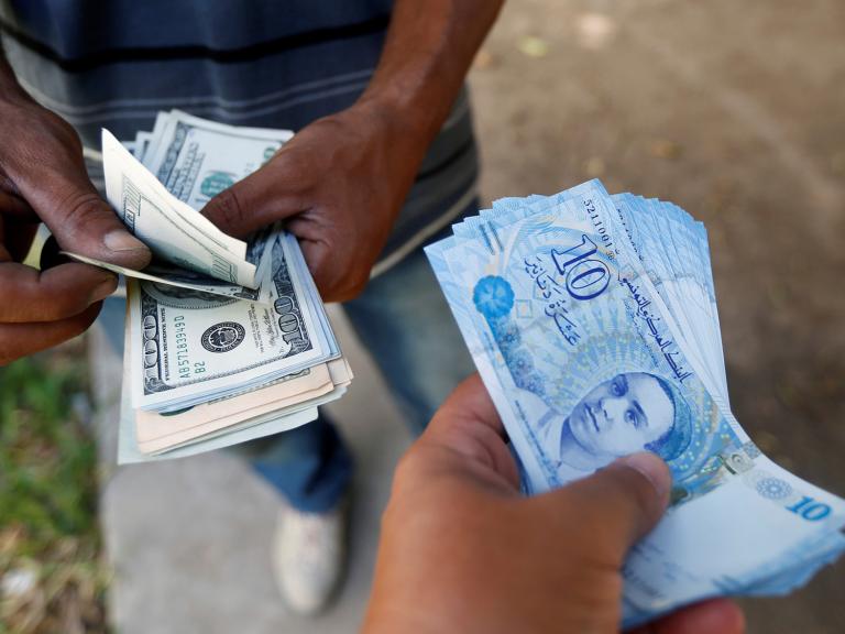 A Tunisian purchases dollars from a money-changer - source: Reuters