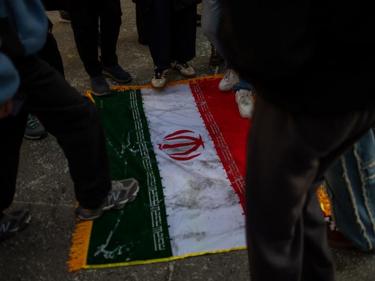 Protesters trample on an Iranian flag - source: Reuters