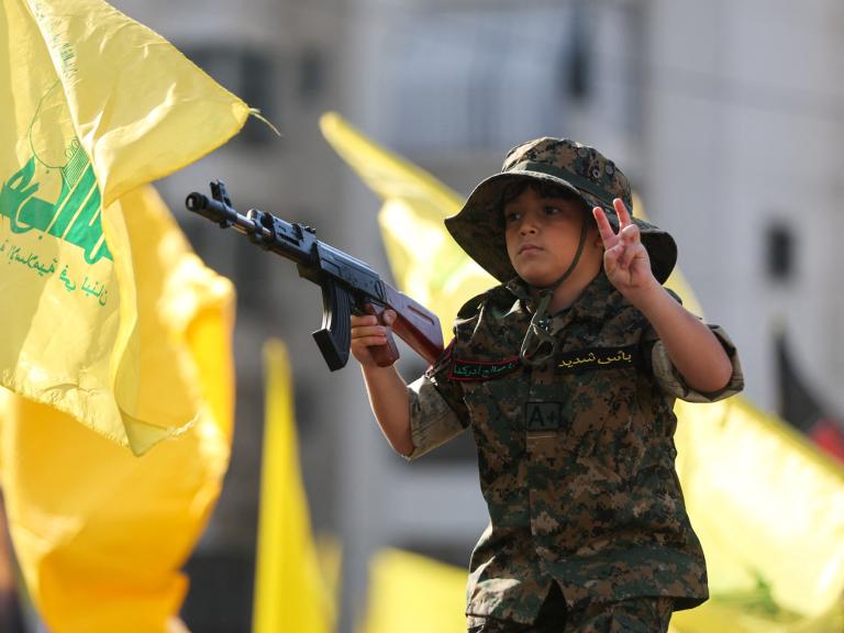A child marches in a Hezbollah parade, holding a toy gun - source: Reuters