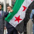 Photo of Syrian Foreign Minister Assad al-Shaibani next to the national flag.