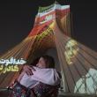Two Iranian women hug each other while a country's flag and a portrait of an Iran-Israel war victim are projected on the Azadi (Freedom) Monument in western Tehran, Iran, on June 25, 2025 - source: Reuters