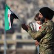 A man holds his child and a flag of the new Syrian regime in Damascus after the fall of the Assad government in 2024 - source: Reuters