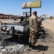 A Sudanese army soldier stands near a bombed-out vehicle outside Khartoum - source: Reuters