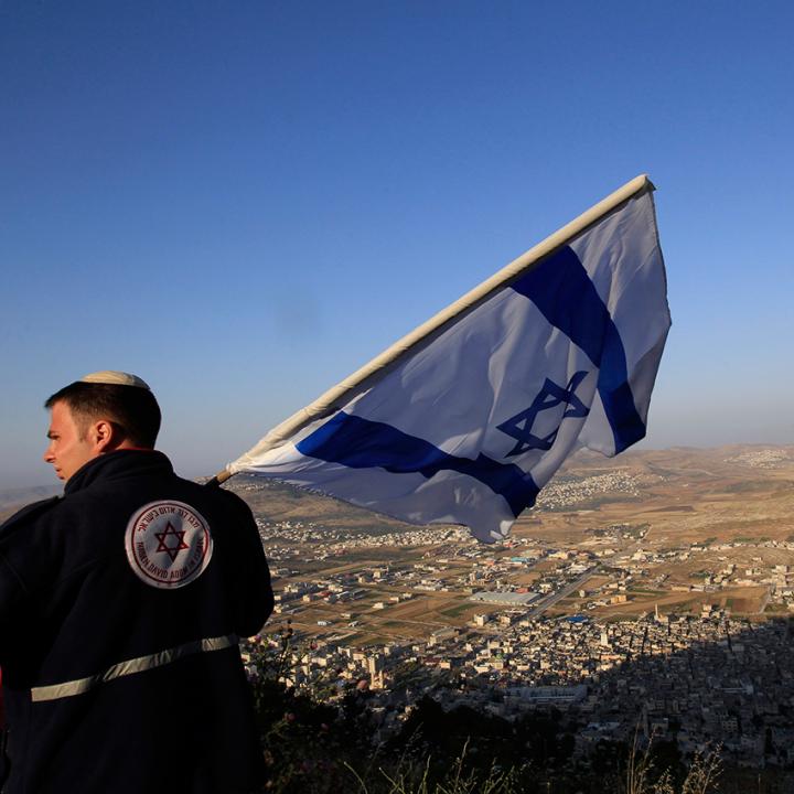 An Israeli settlement activist displays the Israeli flag near Nablus in the West Bank