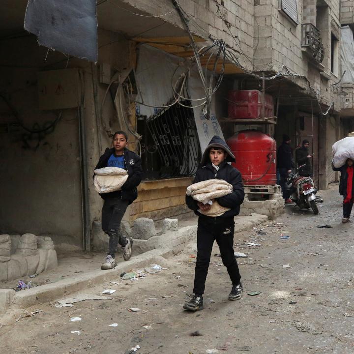 Boys carry bread as they walk along a street in Jaramana, on the outskirts of Damascus, Syria - source: Reuters
