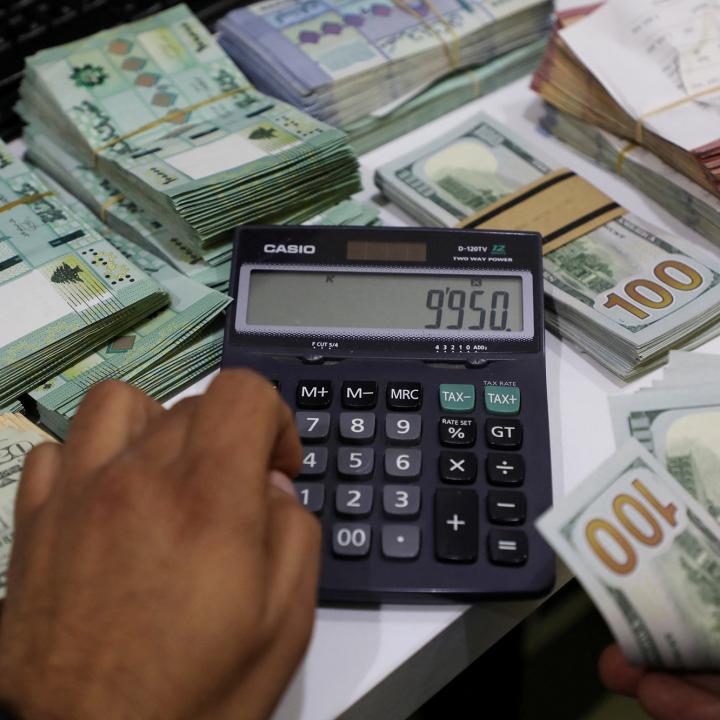 A Beirut money changer handles Lebanese pound and U.S. dollar notes - source: Reuters