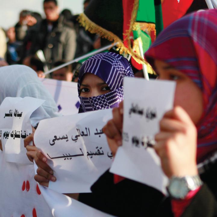 Protesters hold signs and flags in Libya - source: Reuters