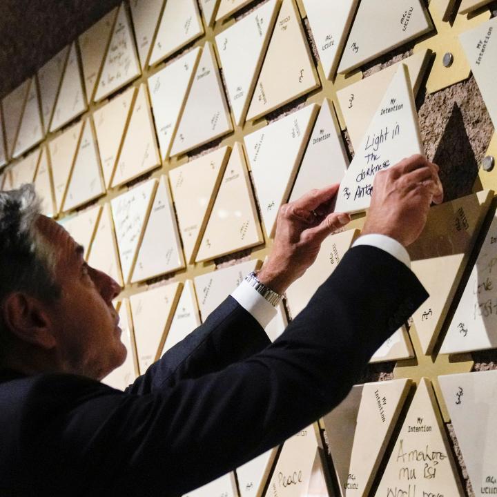 Secretary of State Antony Blinken places a tile that reads "Light in the darkness" on a wall at the Abrahamic Family House in Abu Dhabi, October 14, 2023.