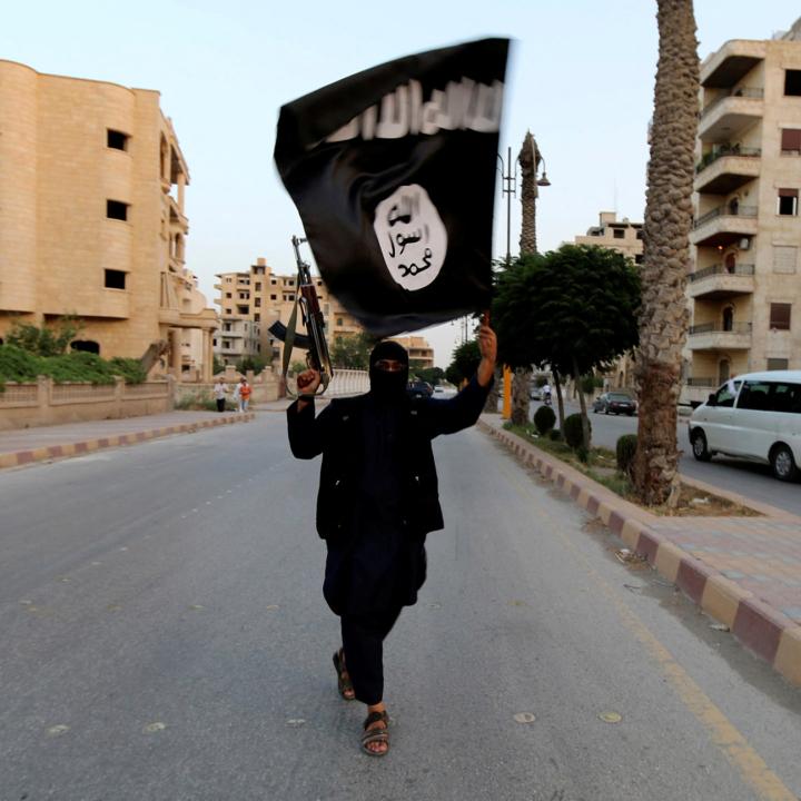 An Islamic State fighter waves an ISIS flag while brandishing an automatic rifle in Raqaa, Syria - source: Reuters