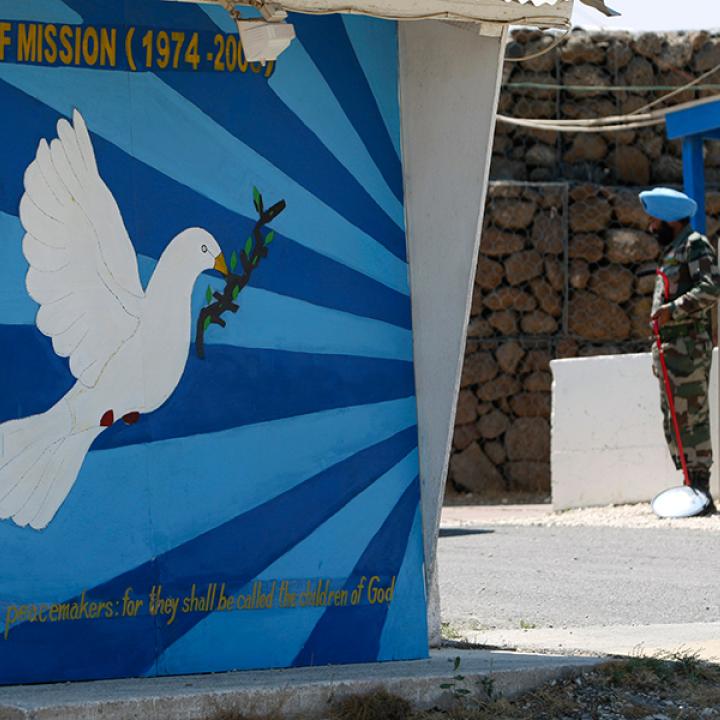 A UNDOF soldier on guard duty next to a mural of a dove of peace - source: Reuters