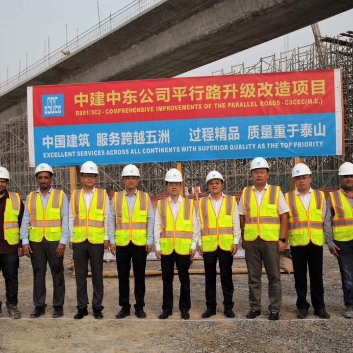 Chinese engineers pose in front of a sign announcing a Belt and Road Project construction project - source: China State Engineering Corp (Middle East) LLC