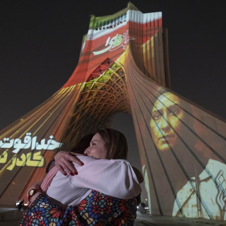 Two Iranian women hug each other while a country's flag and a portrait of an Iran-Israel war victim are projected on the Azadi (Freedom) Monument in western Tehran, Iran, on June 25, 2025 - source: Reuters
