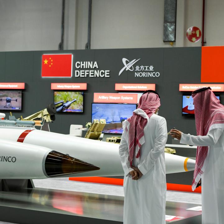 Men stand next to exhibits at the International Defence Exhibition in Abu Dhabi - source: Reuters