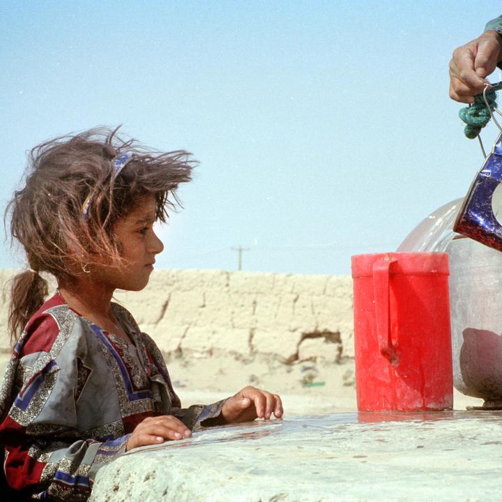 An Iranian girl watches water being poured - source: Reuters