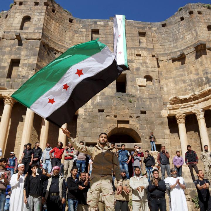 Protesters wave a Syrian opposition flag during a demonstration at a Roman ruin in Deraa Province in 2016 - source: Reuters