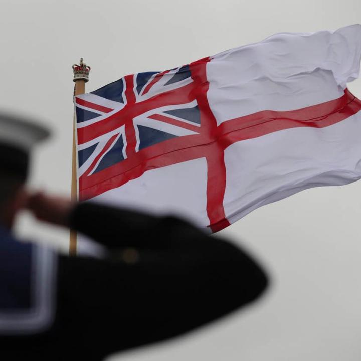 A British sailor salutes the Royal Navy flag - source: Department of Defense