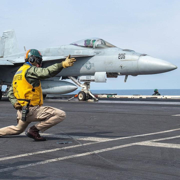 A sailor directs the launch of an F-18 from the flight deck of the carrier USS Harry S Truman - source: Department of Defense