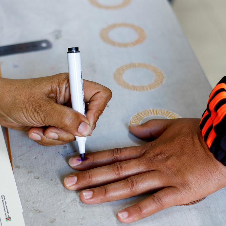 Photo of a Palestinian poll worker inking a voter's finger in Gaza.