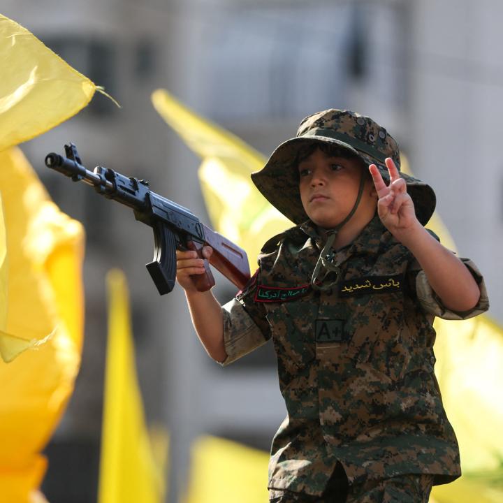 A child marches in a Hezbollah parade, holding a toy gun - source: Reuters