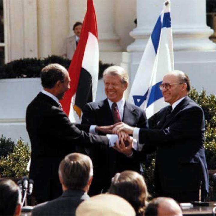 President Jimmy Carter, Egyptian President Anwar Sadat, and Israeli Prime Minister Menachem Begin shake hands at the White House as the Camp David Accords are announced.