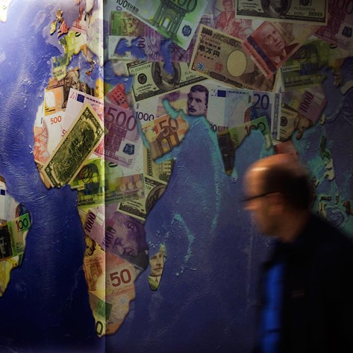 A man walks by a mural of international currencies
