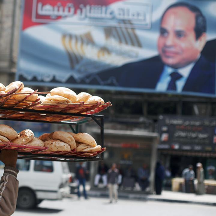 A bread seller in Cairo walks past a sign promoting President Sisi - source: Reuters