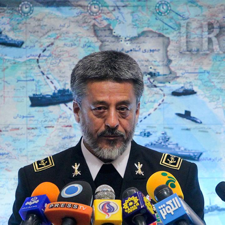 Iran's navy commander speaks in front of a map