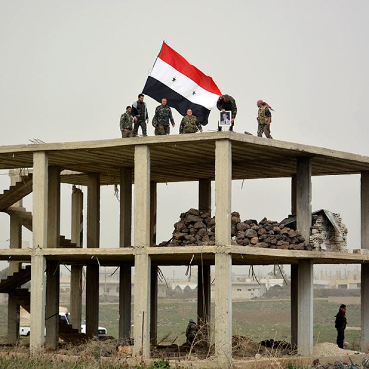 Syrian flag over a ruined building destroyed by bombing