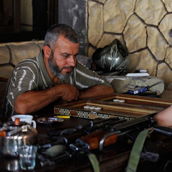 Syrian rebel fighters play a board game in a cafe