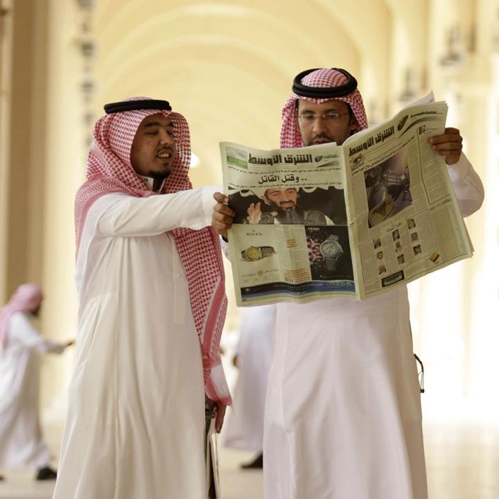 Saudi men read a newspaper - source: Reuters