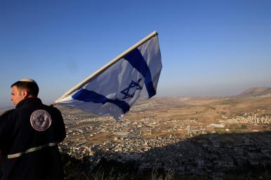 An Israeli settlement activist displays the Israeli flag near Nablus in the West Bank